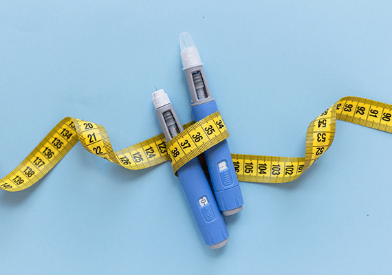 Weight loss concept with two unopened pills wrapped in measuring tape for medical weight management at Fairmont Family Practice in La Porte, TX.